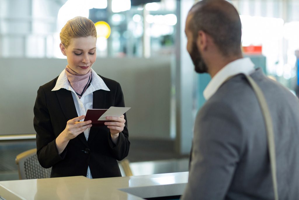 commuter standing counter while attendant checking his passport